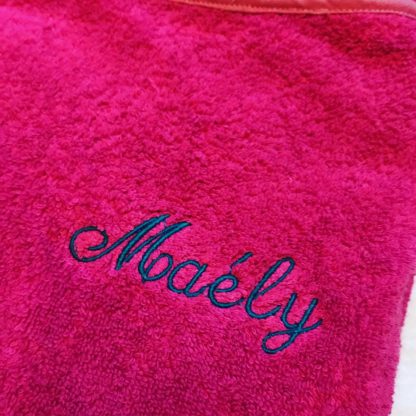 Zoom sur la broderie du drap de bain rose framboise sans capuche, personnalisé avec le prénom Maélys pour exemple